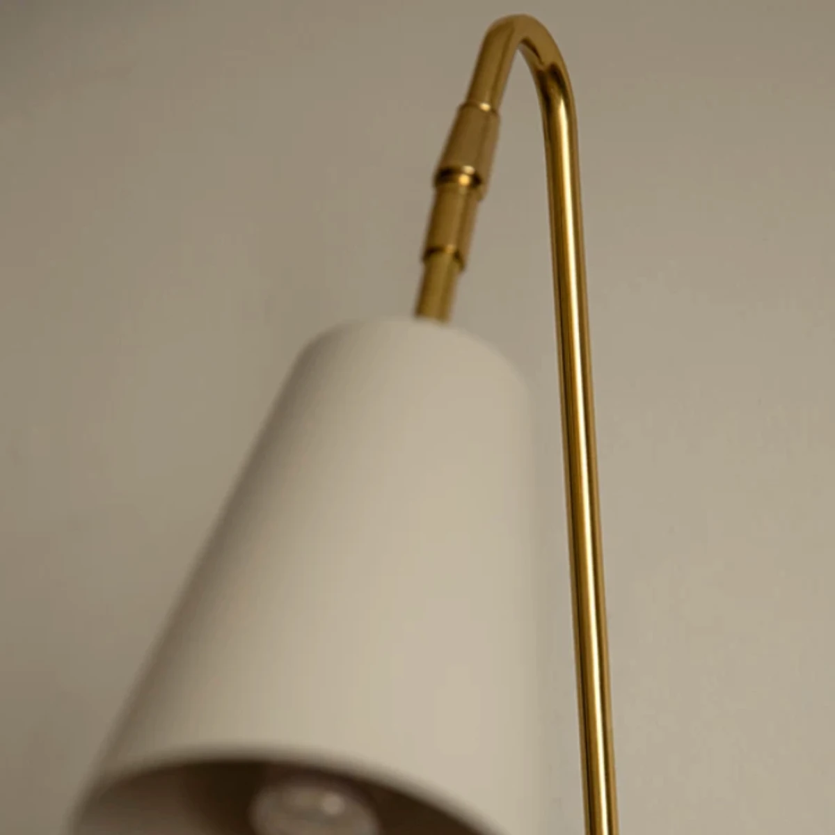 Curved brass arm and white cone shade detail