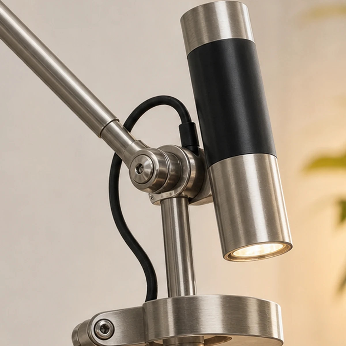 Close-up detail of brushed iron lamp head, pivot joint, and black cord