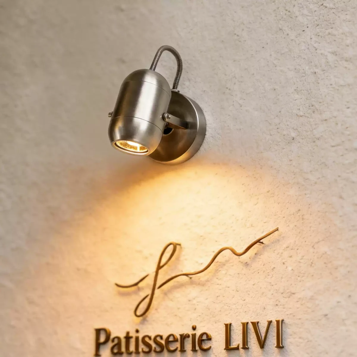 Electroplated sand nickel wall spotlight illuminating a cafe sign
