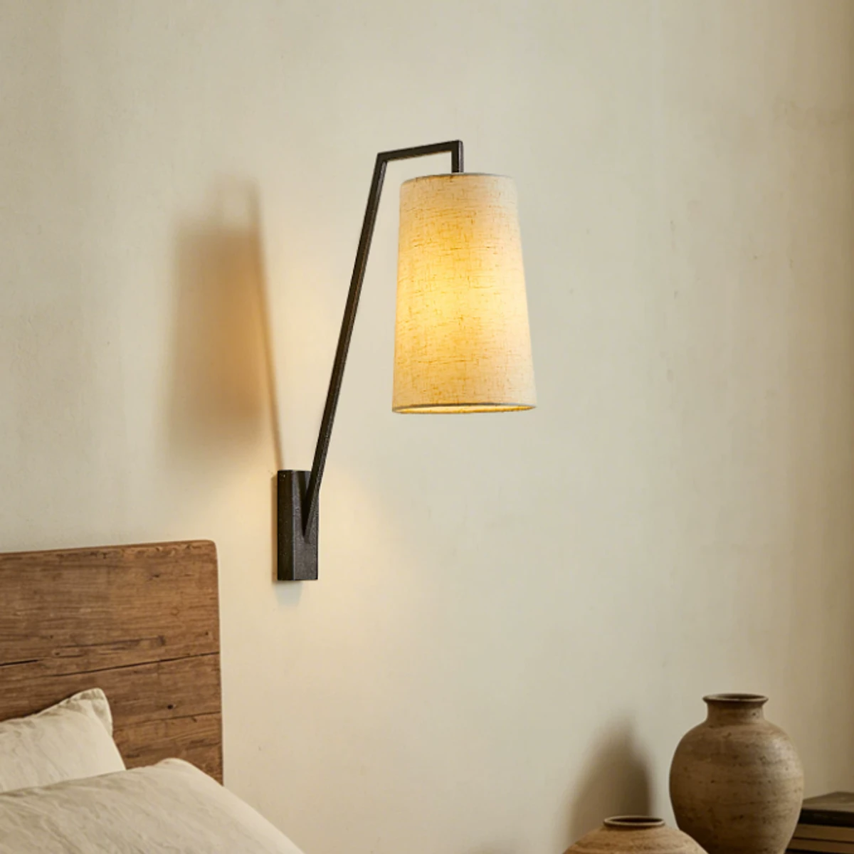 Vintage fabric shade wall lamp by a bedside wall