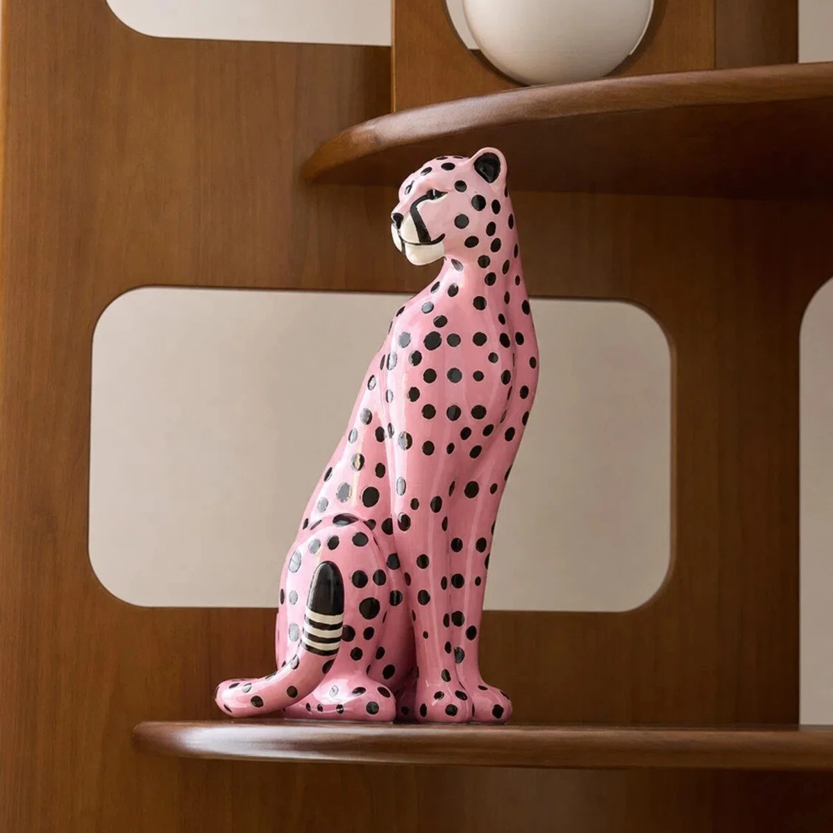 Pink leopard sculpture on a warm wood shelf