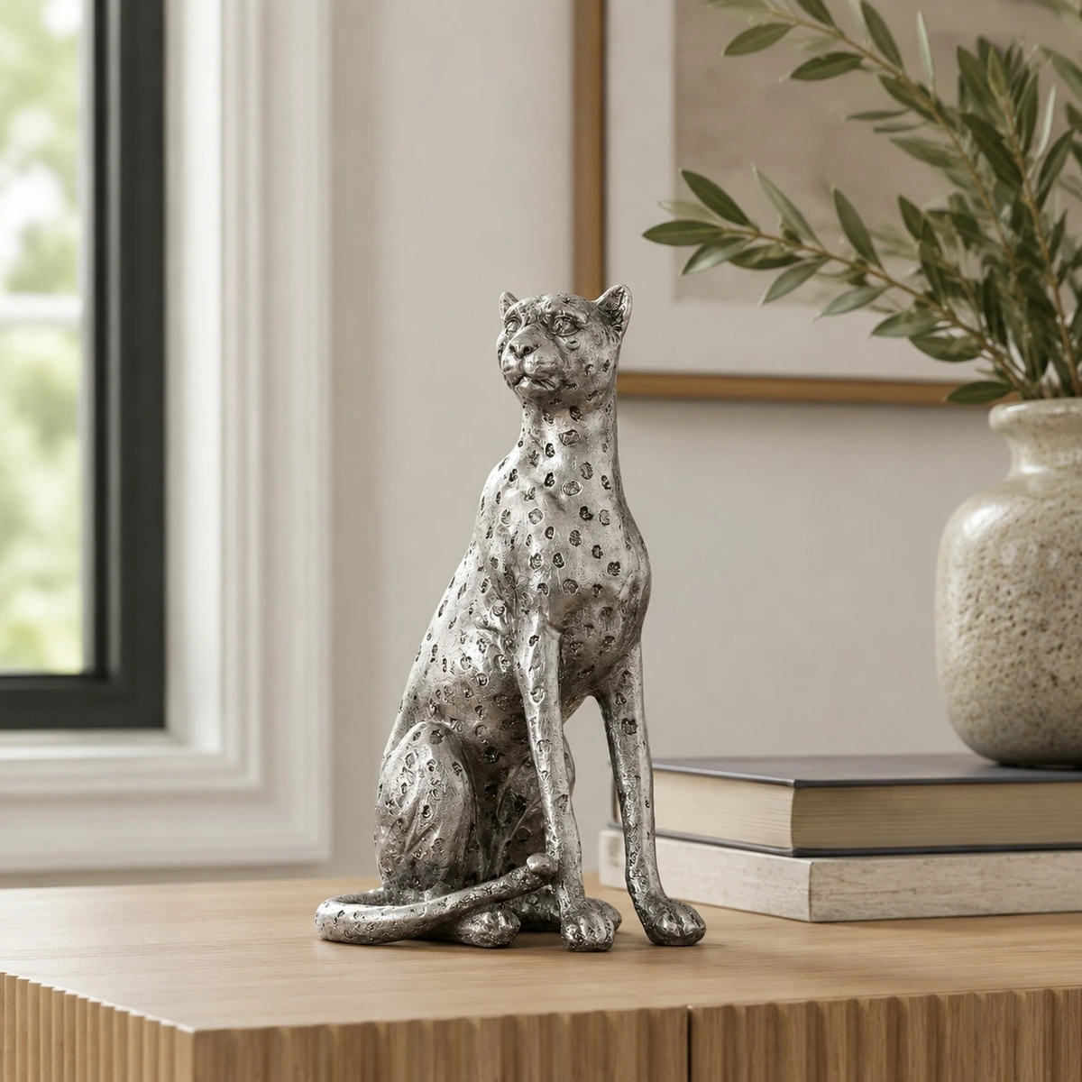 Silver sitting leopard sculpture near a window