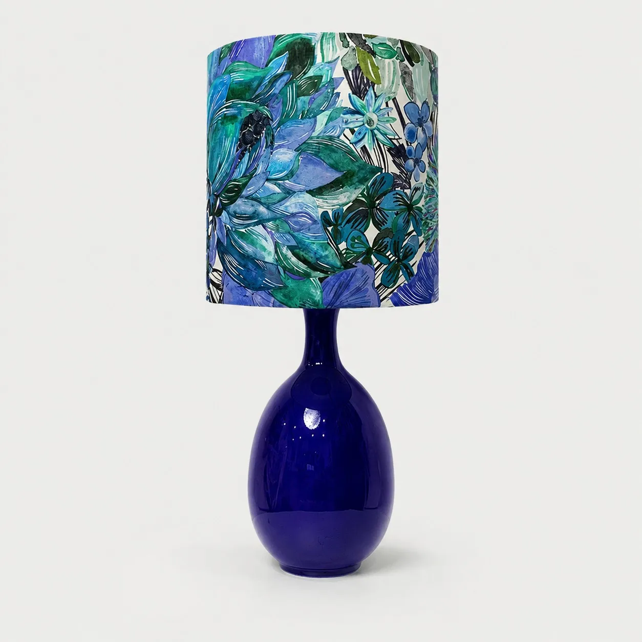 Green botanical fabric ceramic table lamp on plain background